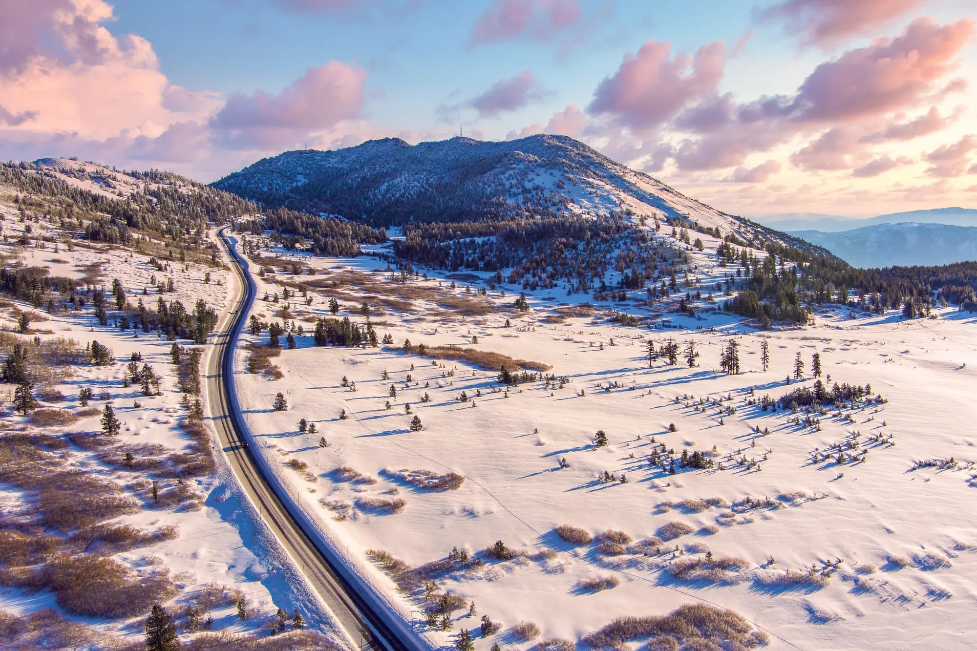 Un camino que serpentea entre colinas nevadas al amanecer