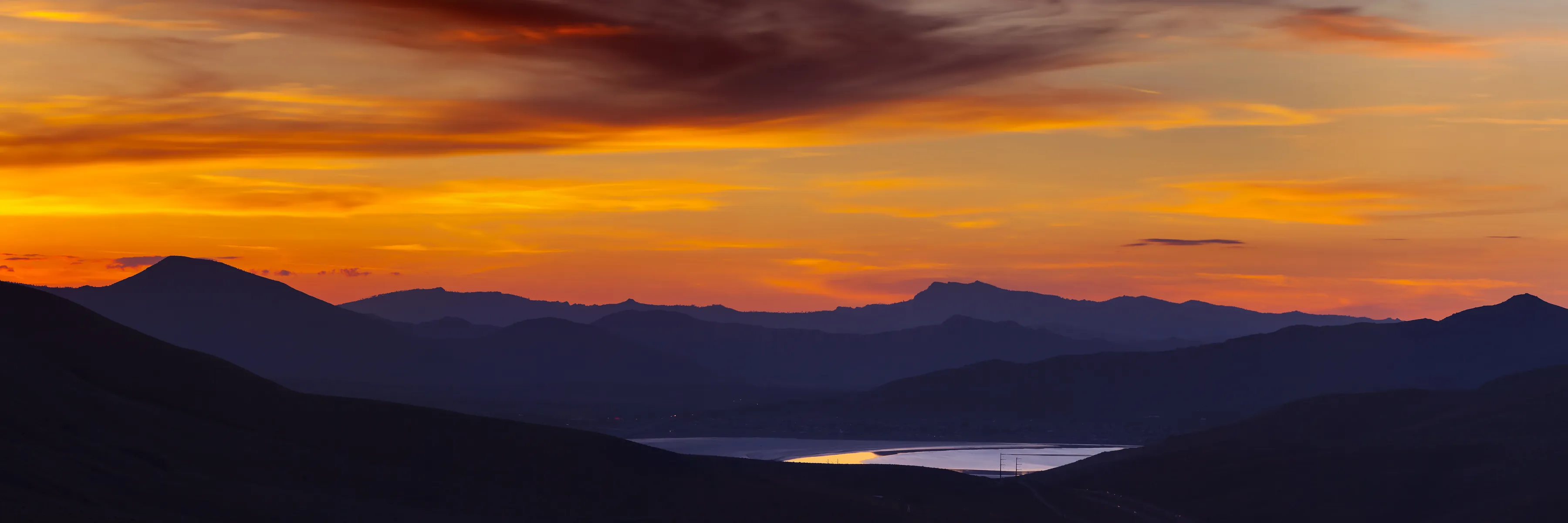Atardecer sobre las montañas y un lago en el valle