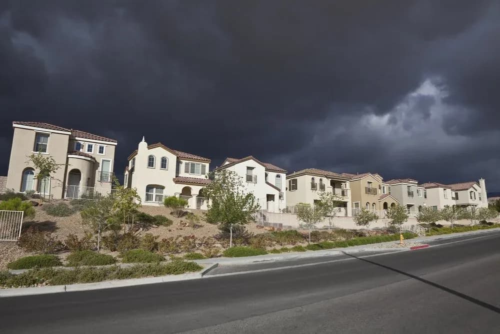 Casas de dos pisos en una calle curva bajo nubes de tormenta