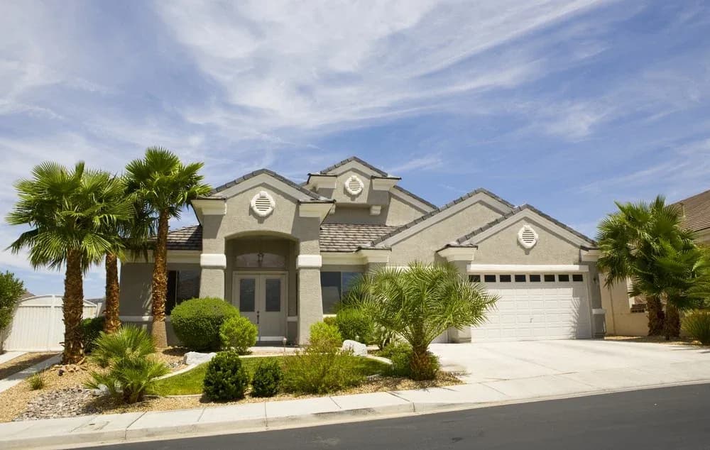 A single-story home with palms and a landscaped front yard