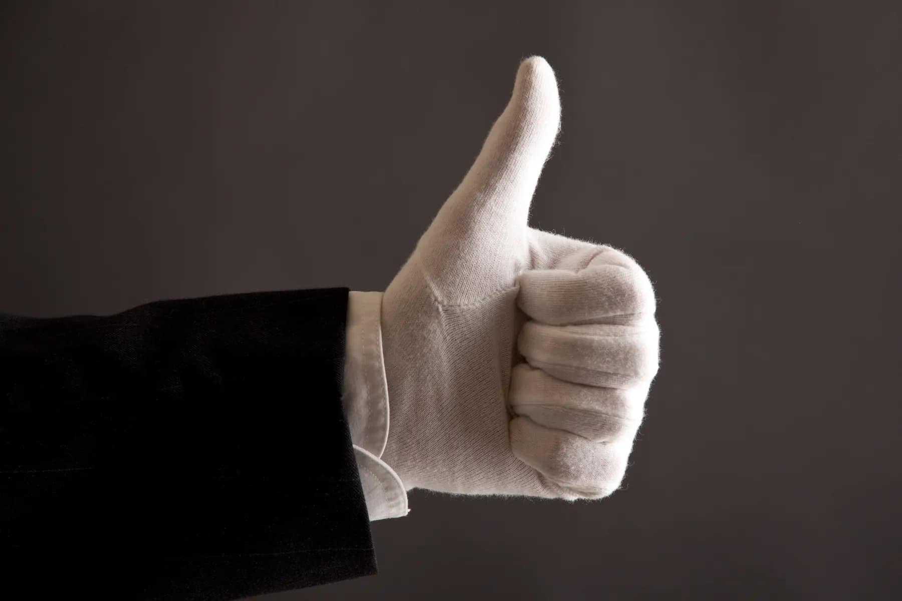 Una mano con guante blanco con el pulgar hacia arriba